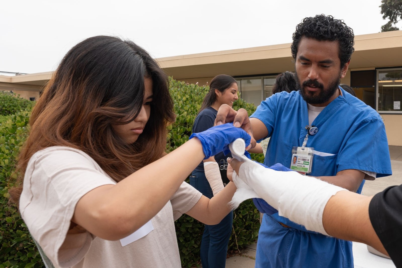 Orthopaedic Surgery resident helps a high school student plaster another student's arm in a demo